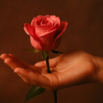 Mano ofreciendo una rosa rosada como símbolo de placer y generosidad
