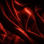 Fotografía artística y tenebrista de pliegues de terciopelo rojo iluminados como un altar sagrado, metáfora visual para el poema erótico "Un coño que diga Amén".